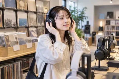 ヘッドホンで音を聞きくらべるお客様（楽器店・レコードの写真 No.24）