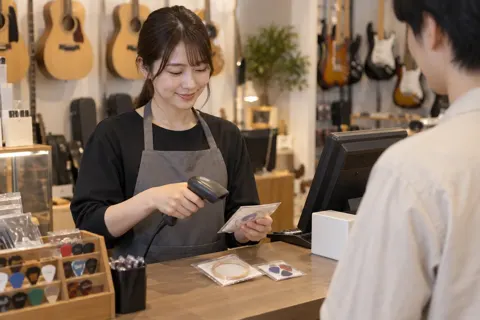 レジで弦やピックを会計する店員（楽器店・レコードの写真 No.32）