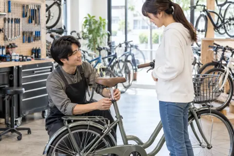 サドルの高さをお客様に合わせる店員（自転車販売・修理の写真 No.34）