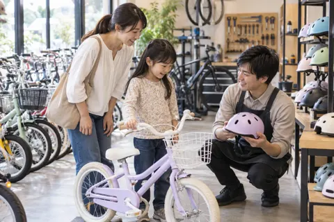 子ども用の自転車とヘルメットをえらぶ親子と店員（自転車販売・修理の写真 No.38）