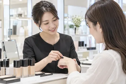 お客様の手の甲でファンデーションの色を合わせる店員（コスメ・化粧品の写真 No.26）