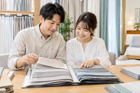 カーテンの見本帳を開いて選ぶ夫婦（寝具・カーテンの写真 No.21）