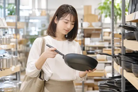 フライパンを持って重さをたしかめるお客様（食器・キッチン用品の写真 No.19）