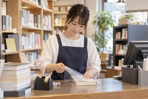 レジで本にカバーをかける店員（書店・古書の写真 No.19）