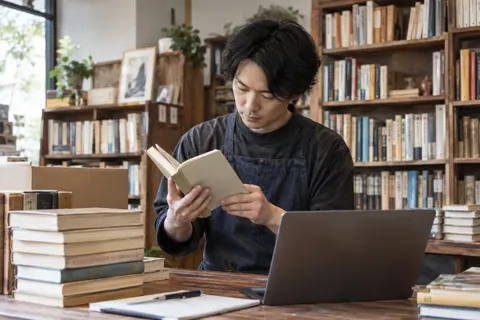 買い取りの本を調べる店主（書店・古書の写真 No.30）