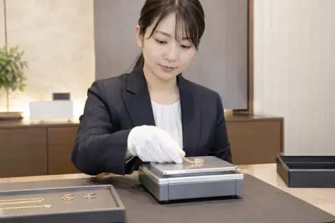 買い取りの品物をはかりにのせる店員（時計・宝飾の写真 No.31）