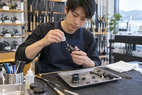 リールを分解して油をさす店員（釣具店・フィッシング用品の写真 No.30）