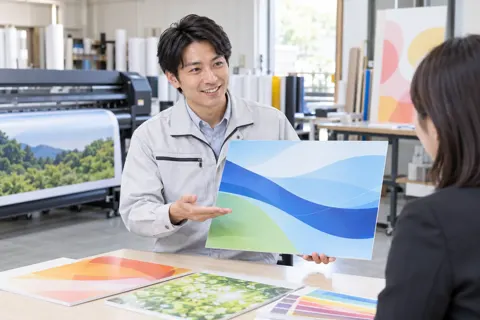 できあがった見本を見せる営業の社員（印刷・看板の写真 No.31）
