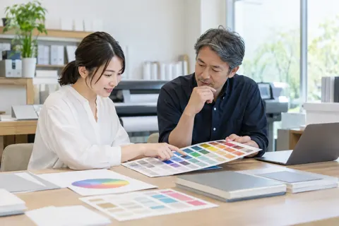 色の見本を見ながら印刷の相談をする二人（出版・編集・ライターの写真 No.21）