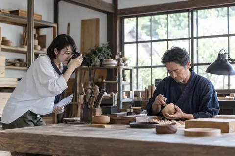職人の仕事場で写真を撮りながら取材するライター（出版・編集・ライターの写真 No.27）