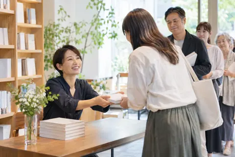 サイン会で読者に本を渡す著者（出版・編集・ライターの写真 No.30）