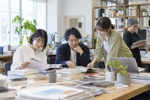 本や雑誌が積まれた編集部の机（出版・編集・ライターの写真 No.35）