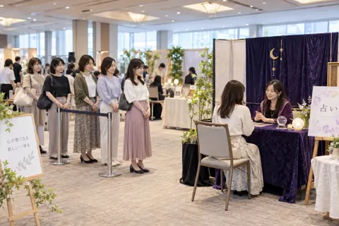 イベント会場の占いのテーブルに並ぶお客様たち（占い・鑑定の写真 No.37）