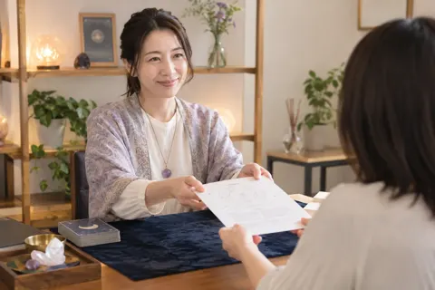 鑑定の結果を書いた紙をお客様にわたす占い師（占い・鑑定の写真 No.40）