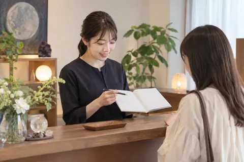 受付で予約の時間を確かめるスタッフ（占い・鑑定の写真 No.45）